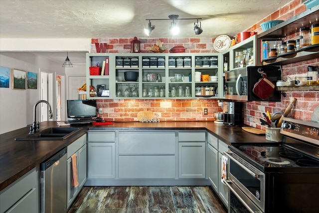 kitchen featuring stainless steel appliances, sink, tasteful backsplash, brick wall, and dark hardwood / wood-style flooring