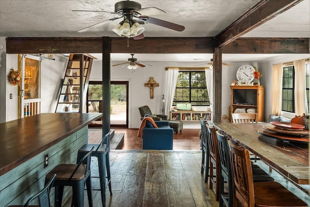 dining space featuring ceiling fan, beamed ceiling, and dark wood-type flooring