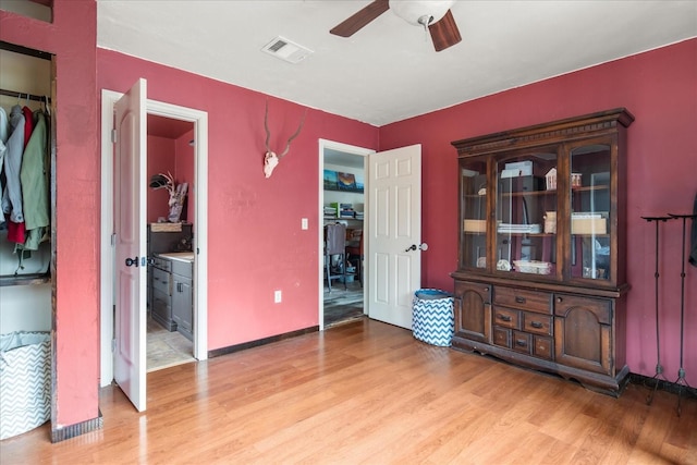 bedroom with ceiling fan, light wood-type flooring, and ensuite bath