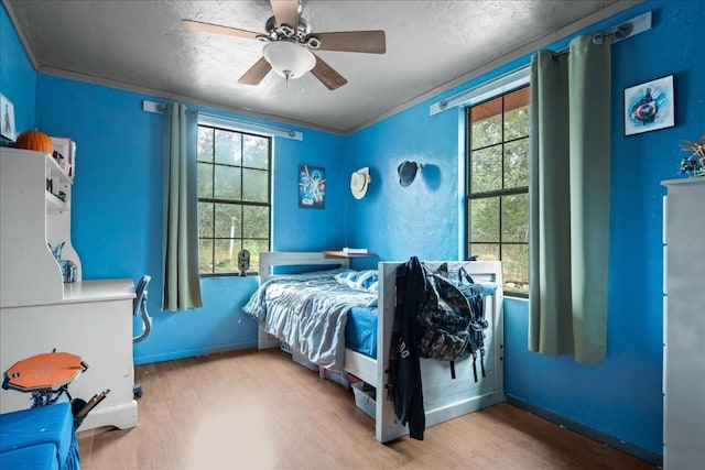 bedroom with ornamental molding, a ceiling fan, baseboards, and wood finished floors