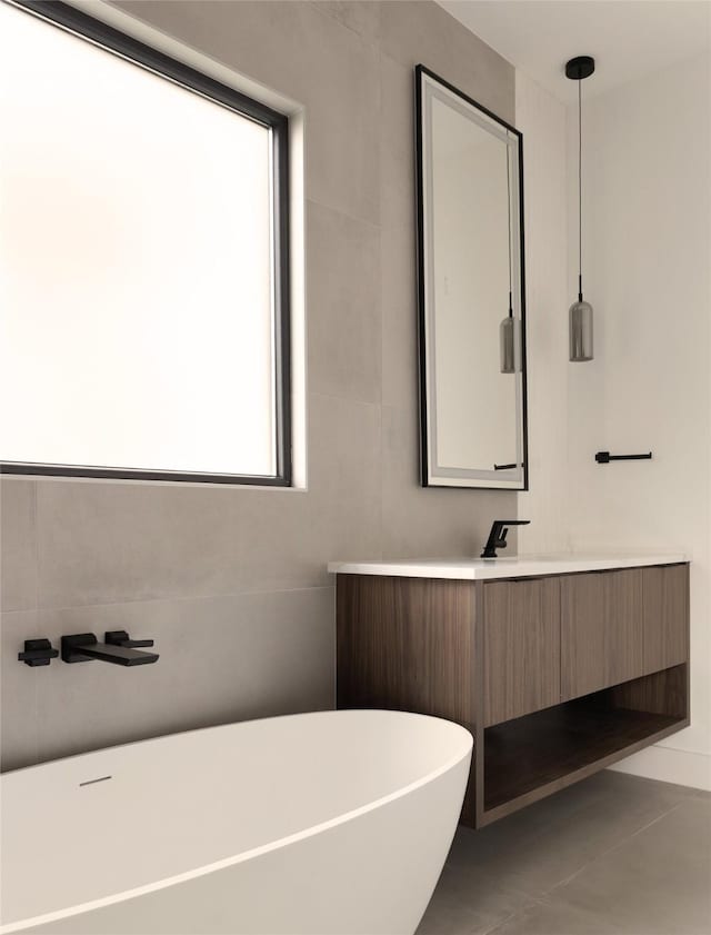 bathroom with a washtub, vanity, and tile patterned floors