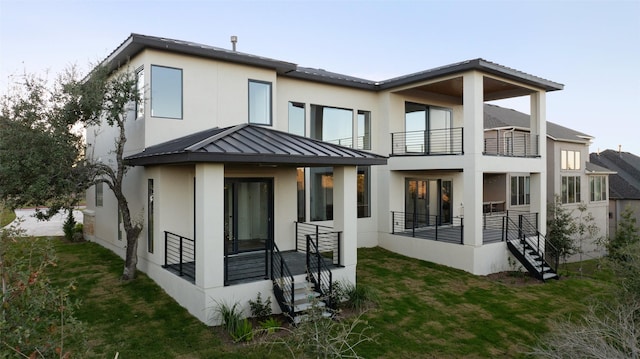 back of property featuring a balcony and a yard