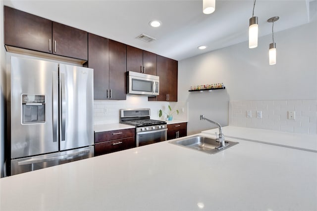 kitchen with decorative light fixtures, appliances with stainless steel finishes, dark brown cabinets, and sink