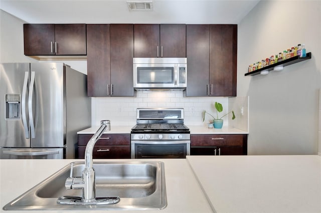 kitchen featuring sink, stainless steel appliances, dark brown cabinets, and backsplash