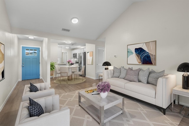 living room featuring lofted ceiling and light wood-type flooring