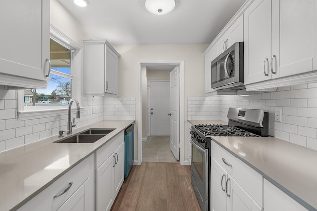 kitchen featuring white cabinets, appliances with stainless steel finishes, dark wood-type flooring, decorative backsplash, and sink