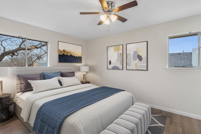 bedroom featuring ceiling fan, multiple windows, and hardwood / wood-style flooring