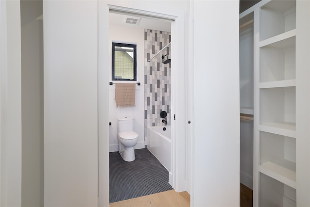 bathroom featuring tiled shower / bath combo and toilet