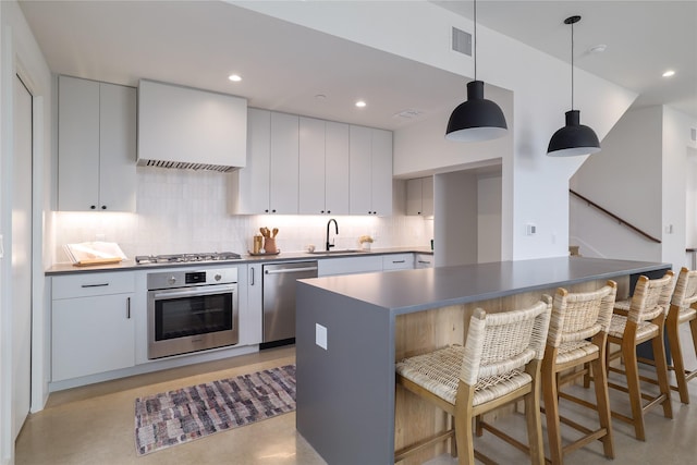 kitchen featuring stainless steel appliances, white cabinets, pendant lighting, and sink