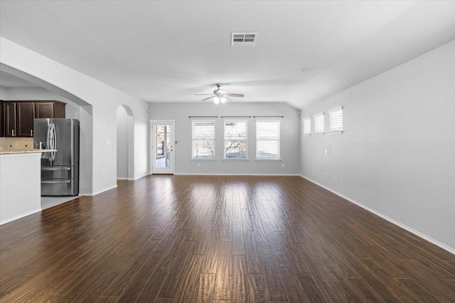 unfurnished living room featuring ceiling fan, vaulted ceiling, and dark wood-type flooring