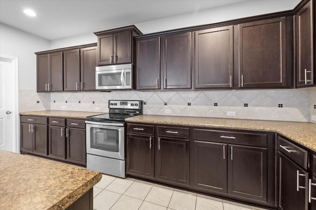 kitchen featuring stainless steel appliances, dark brown cabinets, light tile patterned flooring, and tasteful backsplash