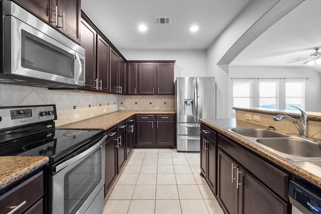 kitchen featuring stainless steel appliances, sink, ceiling fan, light tile patterned floors, and dark brown cabinetry