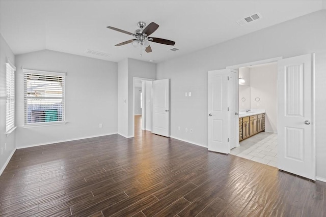 interior space with ceiling fan, connected bathroom, and lofted ceiling