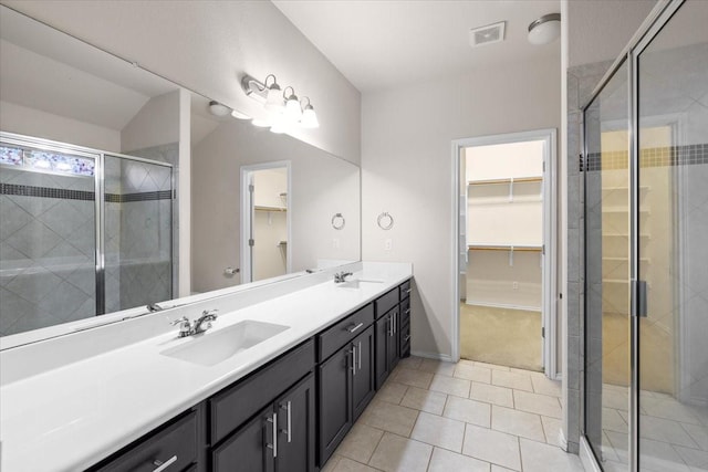 bathroom with a shower with door, vanity, tile patterned flooring, and vaulted ceiling