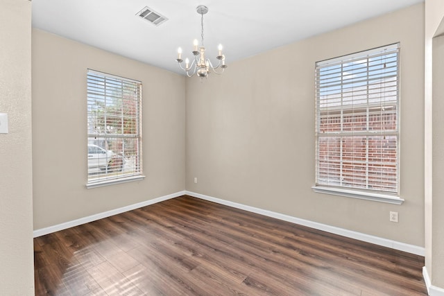 empty room featuring dark hardwood / wood-style flooring and an inviting chandelier