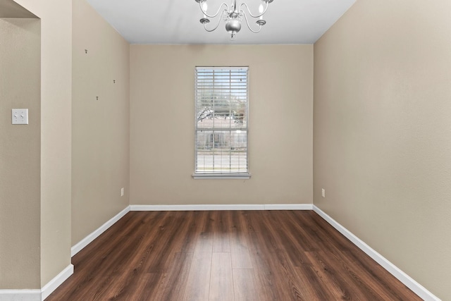 spare room featuring dark hardwood / wood-style floors and a chandelier