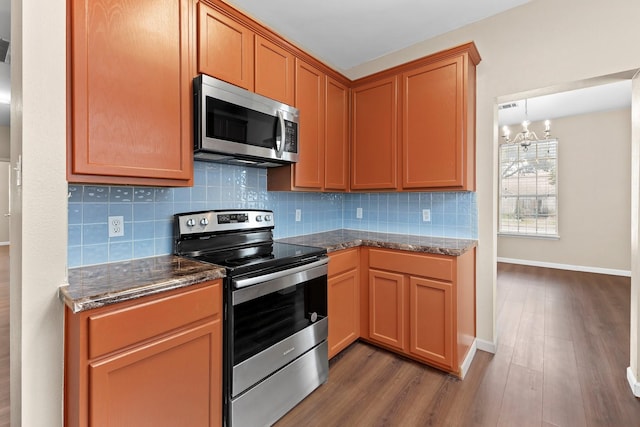 kitchen with dark hardwood / wood-style flooring, decorative backsplash, a notable chandelier, and appliances with stainless steel finishes