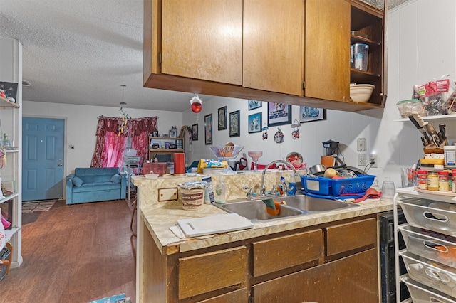 kitchen with kitchen peninsula, dark wood-type flooring, a textured ceiling, and sink