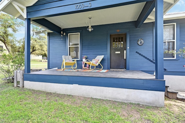 view of exterior entry with a yard and covered porch