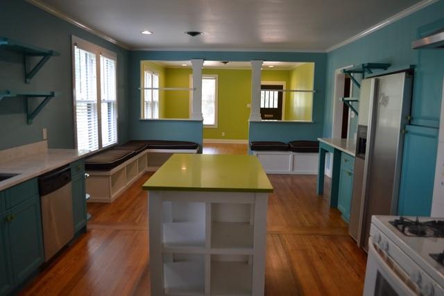 kitchen with crown molding, a kitchen island, wood-type flooring, and stainless steel dishwasher