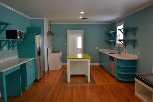 kitchen with ornamental molding, appliances with stainless steel finishes, sink, and wall chimney range hood