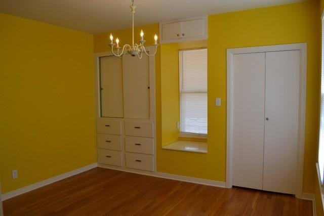 unfurnished bedroom featuring hardwood / wood-style flooring and a notable chandelier