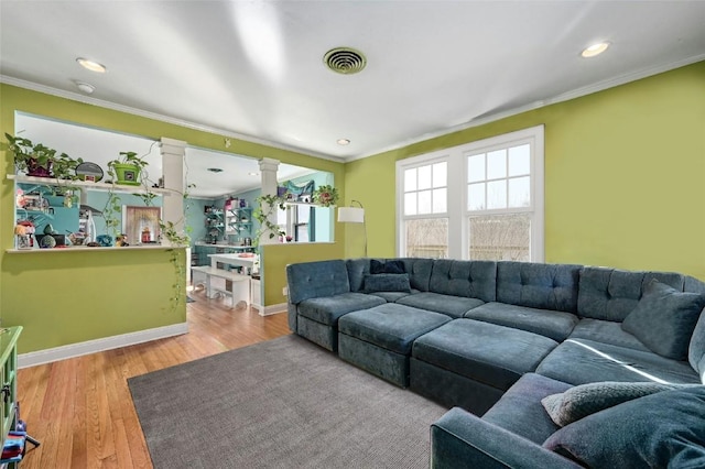 living room with crown molding, light wood-type flooring, and ornate columns