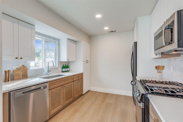 kitchen featuring white cabinets, appliances with stainless steel finishes, light hardwood / wood-style flooring, and sink