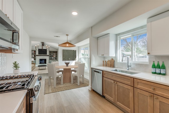 kitchen with decorative light fixtures, stainless steel appliances, plenty of natural light, white cabinets, and sink