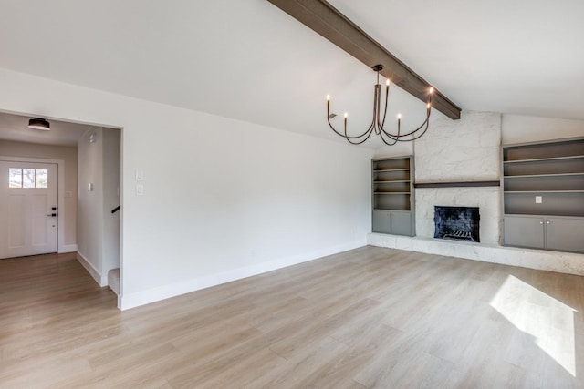 unfurnished living room featuring a fireplace, lofted ceiling with beams, light hardwood / wood-style floors, and a notable chandelier