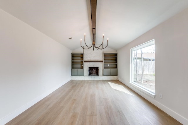 unfurnished living room featuring light wood-type flooring, an inviting chandelier, vaulted ceiling, and a fireplace