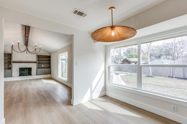 unfurnished living room with vaulted ceiling, a fireplace, a healthy amount of sunlight, and light hardwood / wood-style floors