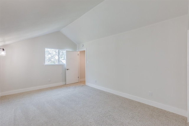 additional living space featuring light colored carpet and vaulted ceiling