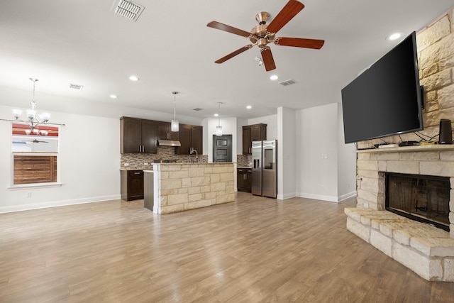 unfurnished living room featuring light hardwood / wood-style floors, ceiling fan with notable chandelier, and a fireplace