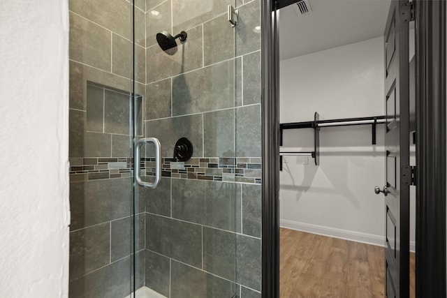 bathroom with hardwood / wood-style floors and a shower with shower door