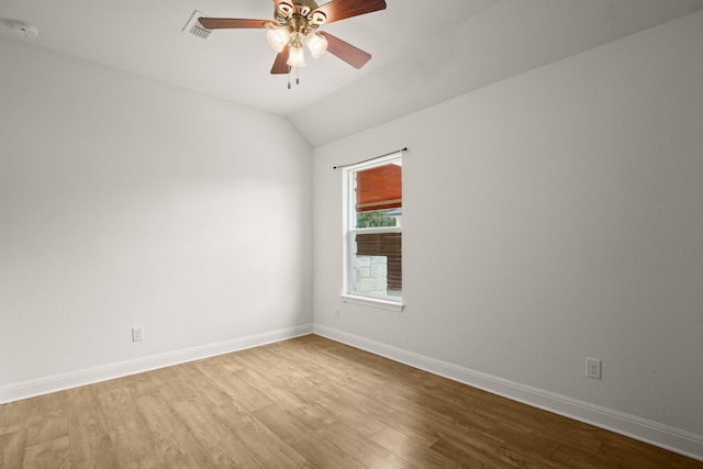 empty room with ceiling fan, vaulted ceiling, and light hardwood / wood-style flooring