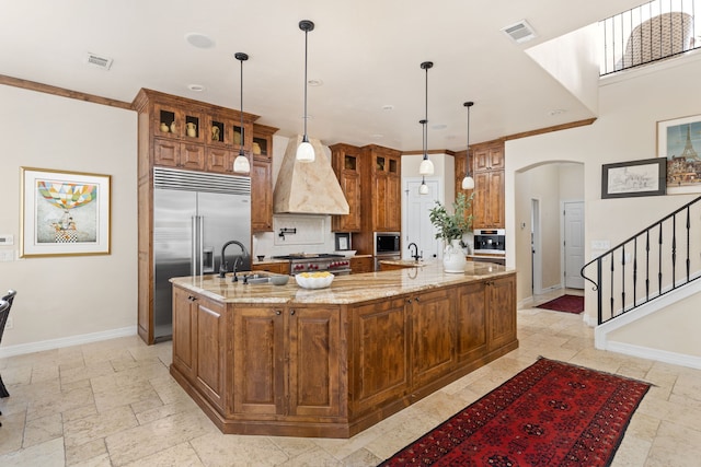 kitchen featuring light stone countertops, decorative light fixtures, a spacious island, crown molding, and sink