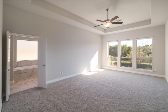 carpeted empty room with a raised ceiling and ceiling fan