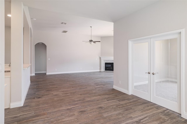 unfurnished living room featuring dark wood-type flooring, a high end fireplace, and ceiling fan