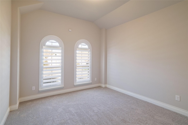 empty room with vaulted ceiling and carpet flooring