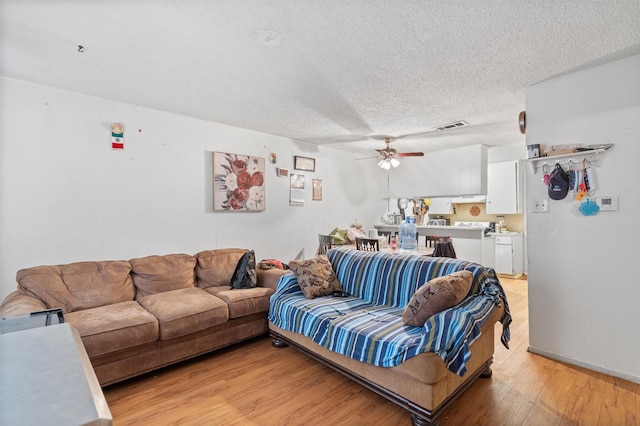 living room featuring a textured ceiling, ceiling fan, and light wood-type flooring