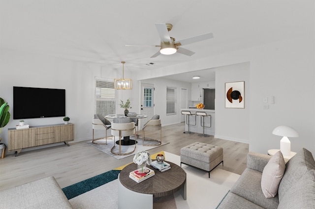 living room featuring ceiling fan with notable chandelier and light hardwood / wood-style floors