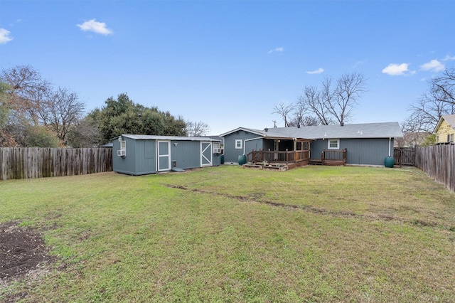 back of property featuring a deck, a storage shed, and a lawn