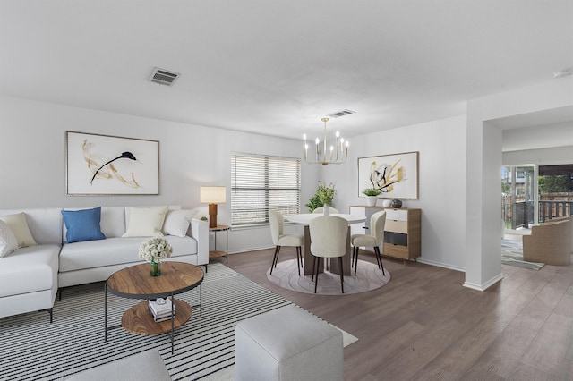 living room featuring dark wood-type flooring, a notable chandelier, and a wealth of natural light