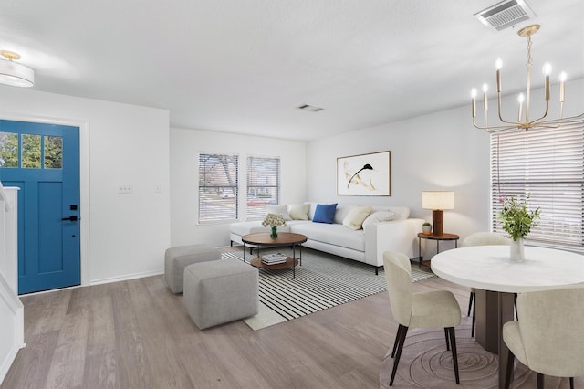 living room with a chandelier, light hardwood / wood-style flooring, and a wealth of natural light