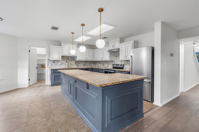 kitchen featuring stainless steel appliances, white cabinets, and a center island