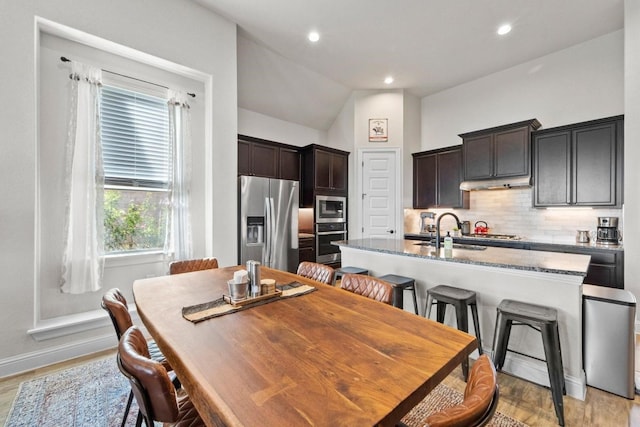 dining area with vaulted ceiling, sink, and light hardwood / wood-style floors