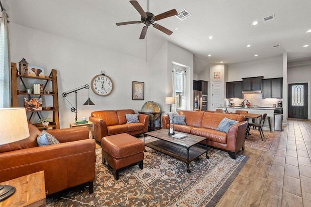 living room with ceiling fan, a towering ceiling, and sink