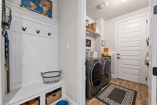 laundry area with light hardwood / wood-style floors, a textured ceiling, and washer and dryer