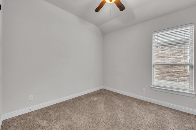 empty room with vaulted ceiling, ceiling fan, and carpet flooring